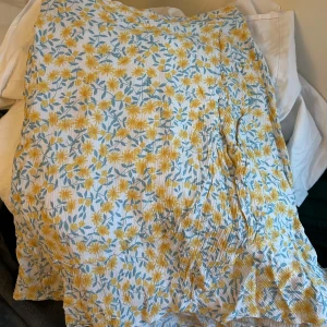 Blommig kjol i bomull - Charmig blommig kjol i bomull med gula och gröna blommor på en vit bakgrund. Kjolen har en lätt och luftig känsla, perfekt för varma dagar. Den har en avslappnad passform och är knälång. Skriv vid frågor eller intresse💞