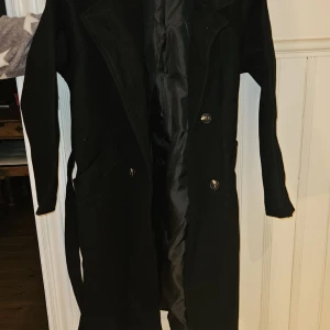 Svart kappa med bälte - Svart kappa från Witchery i storlek S. Helt oanvänd.