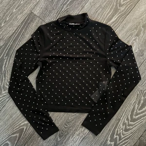 Svart meshtröja med prickar - Snygg svart topp med små silver prickar över hela tyget. Materialet är lätt och genomskinligt