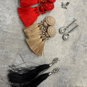 Färgglada örhängen med tofsar och stenar - Säljer flera set med örhängen i olika stilar och färger. Inkluderar röda, beige och svarta tofsörhängen samt glittriga örhängen med stenar. Perfekta för att ge en färgklick till din outfit!