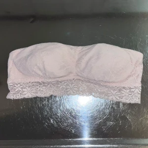 Rosa spets tubtopp från Sassymami - Säljer en söt rosa tubtopp från Sassymami i spets. Toppen har ett vackert blommönster och är perfekt för en stilren look. Den är axelbandslös och har en elastisk kant för bättre passform.