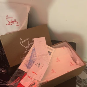 Grå sneakers med nitar från Christian Louboutin - Snygga grå sneakers från Christian Louboutin med nitar på tån och snörning. Skorna har en unik design med en cool och edgy look. Perfekta för att ge din outfit en extra touch.