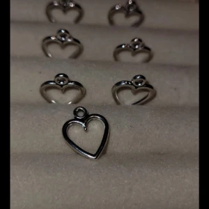 Silverfärgade hjärtformade berlocker - Säljer flera små hjärtformade berlocker i silverfärg. Perfekta för att skapa egna smycken som halsband eller armband. Varje berlock har en liten ögla för enkel fastsättning.