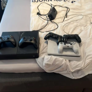 Svart Xbox och vit PlayStation med kontroller - Säljer en svart Xbox med två svarta kontroller och en vit PlayStation med två svarta och en vit kontroll. Perfekt för gamingkvällar med vänner! Inkluderar nödvändiga kablar och strömadapter.