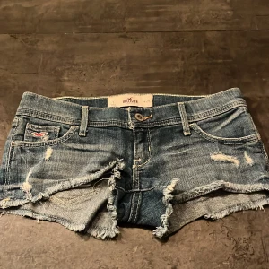 Blå jeansshorts från Hollister - Snygga blå lågmidjade jeansshorts från Hollister i storlek w25 med slitna detaljer och fransar. Dom är i bra skick 💗 midjemåttet framsida är 40cm