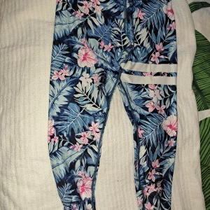 Blommiga leggings från Stronger - Snygga leggings från Stronger med ett tropiskt blommönster i blått och rosa. De har en hög midja och är tillverkade i ett stretchigt material för optimal komfort. Perfekta för träning eller en avslappnad dag.