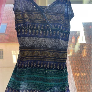 Mönstrad blus från Lindex - Säljer en jättefin ”vintage” blus från Lindex med ett unikt mönster. Påminner om 2000 - talet. Klänningen har en v-ringad design med dekorativa paljetter framtill. Perfekt för dig som vill sticka ut med stil i sommar!! Den va nämligen min mammas gammla som hon använde som klänning, därför är den i storlek L, så jag har sytt in den till strlk S/XS så den sitter bättre i passform. De går hur bra som helst att sprätta upp den, då jag ej har klippt av resterande tyg🤗 Hör av vid intresse!!❤️