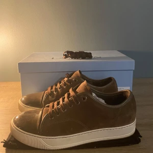 Lanvin uk 6 - Snygga bruna sneakers från Lanvin i mocka med snörning och vit sula. Perfekta för en stilren look. Skorna har en klassisk design med en touch av elegans. Box-extra snören-dust. Skick 9/10 storlek :uk 6. Vid minsta lilla fundering är det bara att kontakta oss. Mvh Nordica Clothing