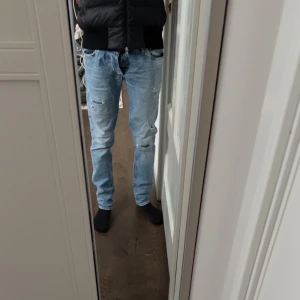 Ljusblå jeans med slitningar från jack&jones - Säljer ett par ljusblå jeans med coola slitningar. De har en klassisk femficksdesign och en bekväm passform. Perfekta för en avslappnad stil. Dem är riktigt feta och i ett otroligt skick 