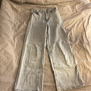 Ljusblå jeansbyxor från Lindex - Säljer ett par ljusblå jeansbyxor från Lindex. De har en avslappnad passform med vida ben och är högmidjade. Perfekta för en casual look. Det finns en liten reva och en fläck som inte går bort i tvätten på ena benet. Är i bra skick storlek 152. Kontakta för mer 🤍