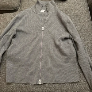 Grå ribbad kofta med dragkedja - Säljer en stilren grå kofta med dragkedja från Ljung. Perfekt sitter väldigt bra och är fint till våren 
