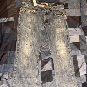 Vintage jeans från Wrangler - Säljer ett par klassiska blå jeans från Wrangler Originals. De har en avslappnad passform med dragkedja och knapp framtill. Jeansen har en snygg tvättad look och fem fickor. Perfekta för en casual stil. Totala längden: 101 cm, midjan tvärs över: 48 cm, benöppning: 23 cm