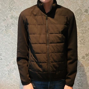 Svart quiltad jacka från Zara - Säljer en stilren svart quiltad jacka från Zara. Jackan har en dragkedja framtill och långa ärmar. Perfekt för våren med sin snygga och funktionella design. Är 178cm och jackan är lite för liten.