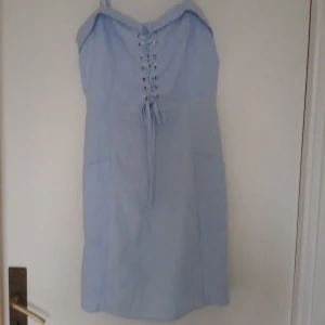 Klänning - Ljusblå klänning, med knyte där fram, dragkedja bak och justerbara ärmar. Kom gärna med prisförslag.