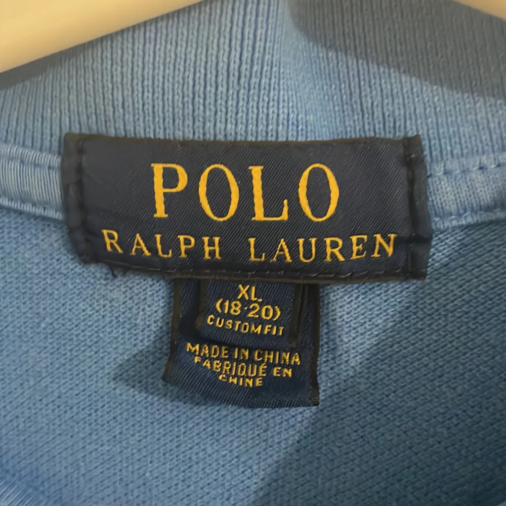 Säljer en snygg blå pikétröja från Ralph Lauren i storlek barn XL som är herr XS . Tröjan har en klassisk krage med två knappar och det ikoniska gula Ralph Lauren-logotypen på bröstet. Perfekt för både vardag och lite finare tillfällen. Passar bra till jeans eller chinos!. Skjortor.