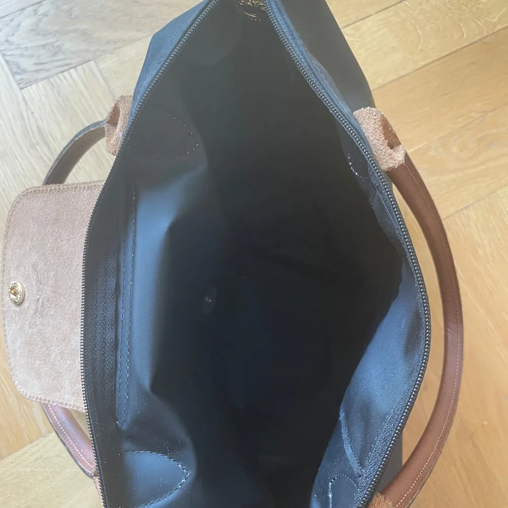 Säljer denna svarta longchamp väska med bruna och guldiga detaljer som är perfekt som skolväska men passar även till annat! Den är helt oanvänd Nypris - 1400kr. Väskor.