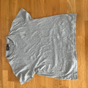 Grå Ralph Lauren T shirt - Säljer min gråa Ralph Lauren t shirt pga ingen användning. Storleken är small och den har en liten defekt i nacken. Det syns inte när man använder den men jag kan sy ihop det innan ni köper det.
