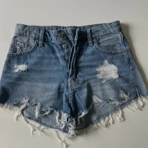 Ett par slitna Jeansshorts med detalj i sidorna.