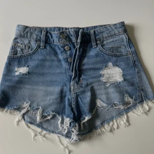 Slitna Jeansshorts  - Ett par slitna Jeansshorts med detalj i sidorna.