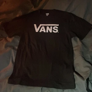 Svart t-shirt från Vans - Säljer en svart t-shirt från Vans i storlek XL vilket motsvarar ungefär XS/S. Iprincip aldrig använd och i nyskick. Den är gjord av 100% bomull och har det klassiska Vans-loggan tryckt i vitt på framsidan.