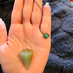 Halsband med grön pendel - Säljer ett snyggt äkta Sten med en grön pendel. Kedjan är i silverfärg och själva pendeln är en grön sten som är formad som en kon. Perfekt för att lägga till en touch av mystik till din outfit!