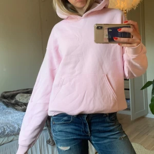 Ljusrosa hoodie - Säljer en supermysig ljusrosa hoodie som är perfekt för chilliga dagar. Den har en stor ficka fram och en skön huva. Passformen är lite oversized vilket gör den extra bekväm. Perfekt för höst och vår!