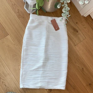 Snygg vit pennkjol - Kjolen är helt oanvänd med etikett på.  Storlek M men passar både S och M.  Färgen är helt vit