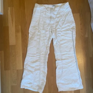 Lågmidjade raka linnebyxor - Vita raka linnebyxor med låg midja Midjemått: ca 75 cm Innerbenslängd: ca 65 cm (Personen på bilden är ca 160 cm) Ett litet hål på baksidan, se bild 