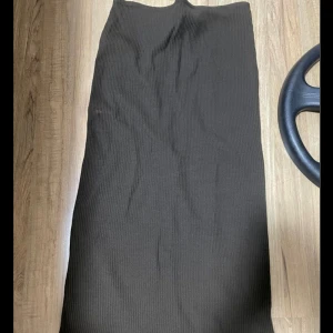 Svart ribbad kjol - Säljer en stilren svart ribbad kjol som är perfekt för både vardag och fest. Kjolen har en lång modell och är gjord i ett mjukt och stretchigt material som ger en bekväm passform. Den är enkel att matcha med olika toppar och accessoarer. Perfekt för höst och vinter!