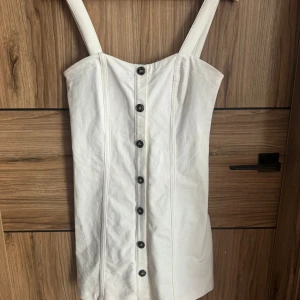 Vit klänning från H&M - Säljer en vit klänning från H&M i storlek S. Klänningen har knappar framtill och breda axelband. Perfekt för sommarens alla tillfällen! 🌞