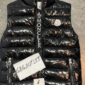 Svart dunväst från Moncler - Säljer en snygg och glansig svart dunväst från Moncler. Västen har en quiltad design med dragkedja framtill och två praktiska fickor med dragkedjor. Perfekt för höst och vinter för att hålla värmen med stil. Moncler-loggan syns tydligt på bröstet.