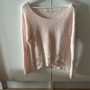 Ljusrosa stickad tröja - Säljer en superfin ljusrosa stickad tröja. Den är långärmad och har en lös passform som gör den perfekt för både vår och höst. Tröjan har en rund hals och en snygg, lite sliten look med fransar längst ner. Perfekt för en avslappnad och stilren outfit! 💖