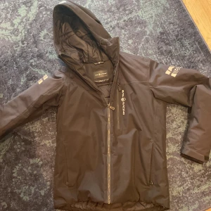 Svart jacka från Sail Racing - Säljer en svart jacka från Sail Racing i storlek medium. Jackan har en stilren design med dragkedja och huva. Perfekt för kyliga dagar och har en sportig look. Den är  i bra skick och redo för nya äventyr! Helt oanvänd och pris kan diskuteras 