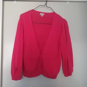 Rosa kofta med knappar - Säljer en superfin rosa kort kofta i storlek M. Den har en djup v-ringning och knappar framtill. Perfekt för både vår och sommar, och den är i bra skick. Passar perfekt till både jeans och kjol!
