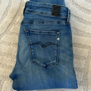 Blå jeans från Replay - Säljer ett par nästintill oanvända blå jeans från Replay, modellen Luz. De har en klassisk femficksdesign med en knapp och dragkedja framtill. Jeansen är i en slim passform samt lowwaist och har en snygg tvätt som ger dem en cool look. 