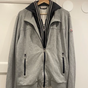Grå Moncler cardigan  - Säljer denna snygga monclear cardigan i mycket bra skick utan defekter och märken. Det står att plagget är i XXL men det sitter som L och funkar som M. Tveka inte att kontakta för fler bilder eller funderingar!