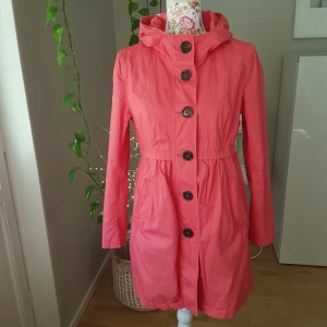 Tunn vårkappa i bomull, från H&M - Härlig, korallfärgad kappa. Blommigt foder & knäppning. Kraftigare, men rätt tunt bomullstyg.. typ canvas. Mycket fint, begagnat skick! ~ STOR rensning & erbjudanden i min shop ~ Köp en jacka/kappa/väst & välj till en mössa, gratis ! ~
