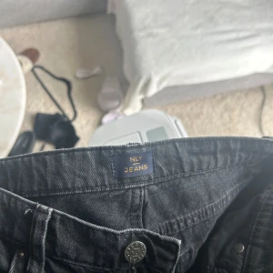 Jeans Nelly  - Lågmidjade jeans från Nelly,utsvängda med en slit svart/grå S/Xs