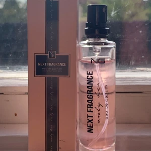 Next Fragrance Eau de Parfum - Säljer en elegant och fräsch parfym från Next Generation Perfumes. Flaskan är genomskinlig med en stilren design och innehåller en rosa vätska. Doften är en eau de parfum, vilket betyder att den har en högre koncentration av doftoljor och håller längre. Perfekt för både vardag och speciella tillfällen!