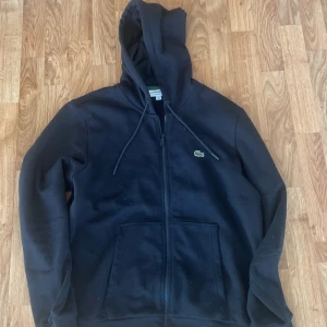 Lacoste zip hoodie  - Säljer min svarta Lacoste Hoodie den är som ny Max använd 4 gånger köpte den inga defekter grymt skick, kan gå ner i pris vid snabb affär 