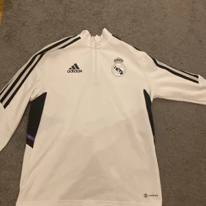 Vit långärmad fotbollströja från Adidas - Säljer en vit långärmad fotbollströja från real Madrid och 22/23 säsongen, skicket är bra då den mest har legat i garderoben, nypris låg runt 750kr från unisport, de är perfekt för all sorts träning, hör av er om ni har några funderingar 
