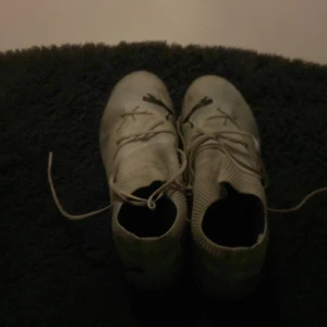 Grå fotbollsskor med snörning - Säljer ett par vita fotbollsskor med snörning. Skorna har en stilren design och är perfekta för fotbollsplanen.