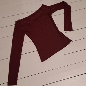 Vinröd offshoulder topp - Snygg vinröd offshoulder topp med långa ärmar och ribbad design. Perfekt för en stilren look.