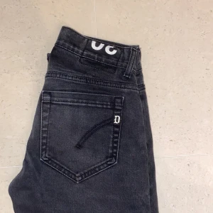 Dondup jeans George - Snygga svarta skinny jeans från George med en unik detalj av ögon på insidan av midjan. Perfekta för en stilren look med en twist. De har en klassisk femficksdesign och knappgylf. Jeansen är i underbart skick. Samt går det att lägga till lite egna slitningar på jeansen om du vill stå ut lite mer. Storlek 30 först till kvarn 699kr! 