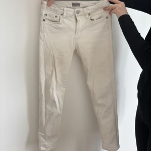Vita cropped jeans från Filippa K - Snygga vita cropped jeans från Filippa K i storlek S. De har en klassisk design med fem fickor och knappgylf. Perfekta för en stilren look.