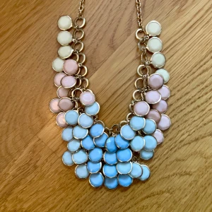 Färgglatt halsband med cirkulära detaljer bijouteri - Snyggt halsband med cirkulära detaljer i pastellfärger. Det har en kedja i guldton och detaljer i vitt, rosa och blått. Köpt i Barcelona men aldrig använt.