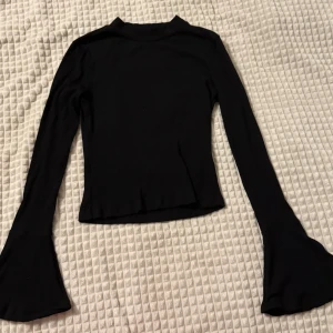 Svart långärmad topp med utsvängda ärmar - Snygg svart långärmad topp med utsvängda ärmar. Perfekt för en stilren look. Passar bra till både jeans och kjol. Om ni vill se den på, skriv gärna!