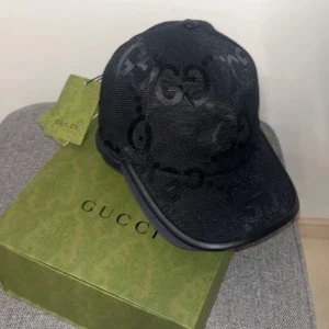 Svart keps från Gucci - Snygg svart keps från Gucci med det ikoniska GG-mönstret. Kepsen har justerbar rem baktill för perfekt passform och är tillverkad i ett slitstarkt material. Perfekt för att ge din outfit en lyxig touch.