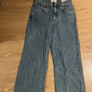 Blå wide leg jeans från Cotton On - Säljer ett par snygga blå wide leg jeans från Cotton On. De har en avslappnad passform och är perfekta för en trendig look. Jeansen har klassisk femficksdesign och knappgylf.