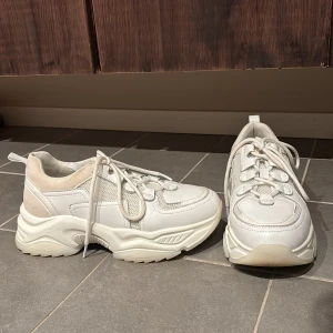 Vita chunky sneakers från NA-KD - Snygga vita chunky sneakers från NA-KD med snörning och en rejäl sula. Perfekta för en trendig look. Tillverkade i syntetmaterial med detaljer i beige.